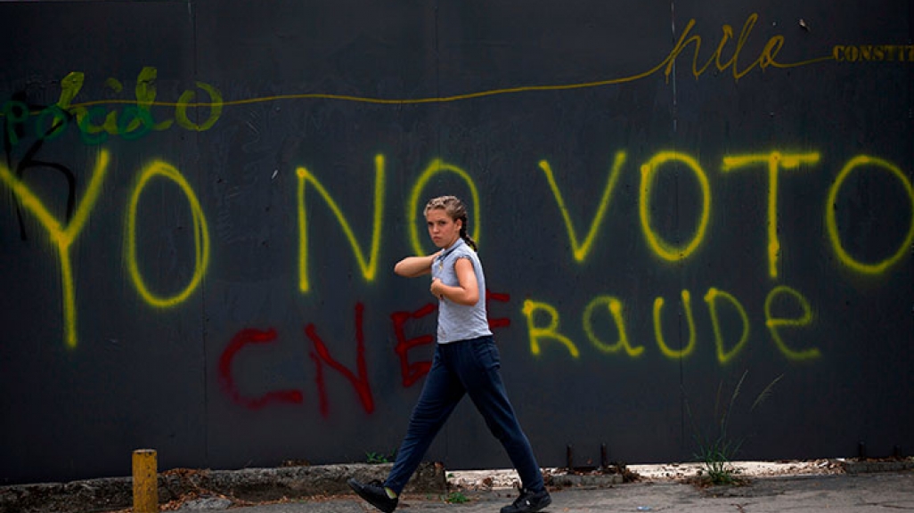 A Venezuelan walks past a wall with graffiti that reads "I won't vote."