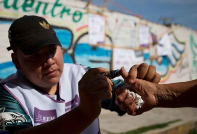 An Mexican election worker marks a voter's thumb with ink.