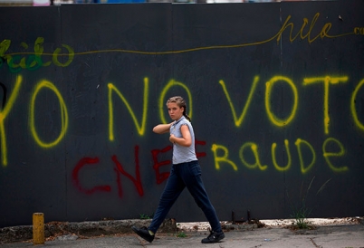 A Venezuelan walks past a wall with graffiti that reads "I won't vote."