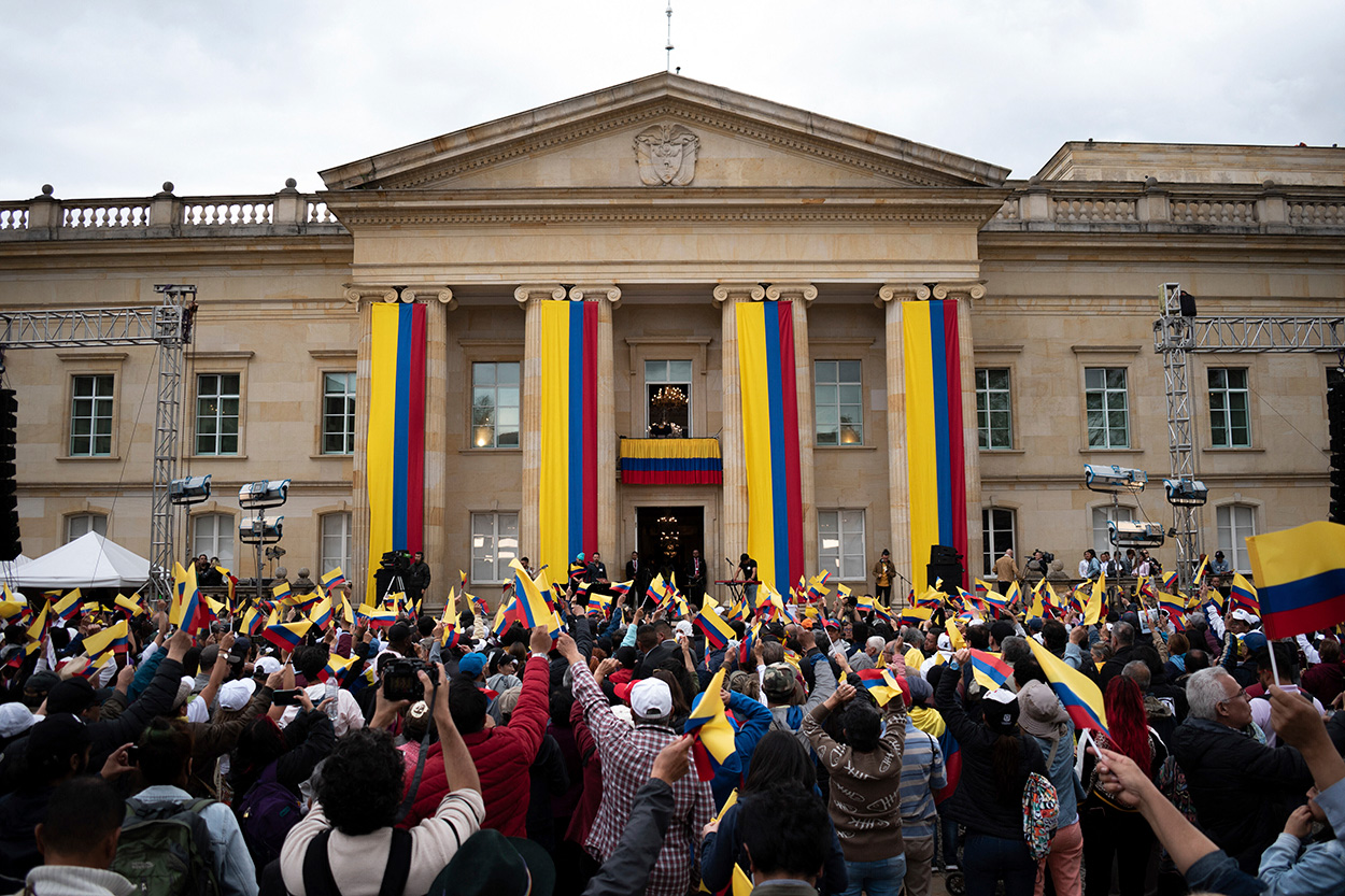People gather at Colombia's presidential palace in Bogotá waving the yellow, blue, and red flag. (AP)