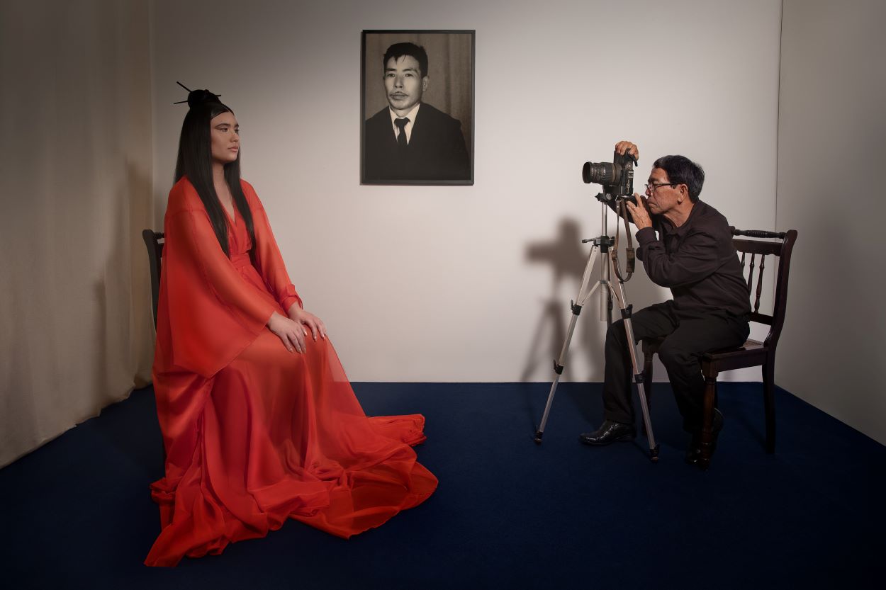A woman with a red dress posing and a photographer taking her picture