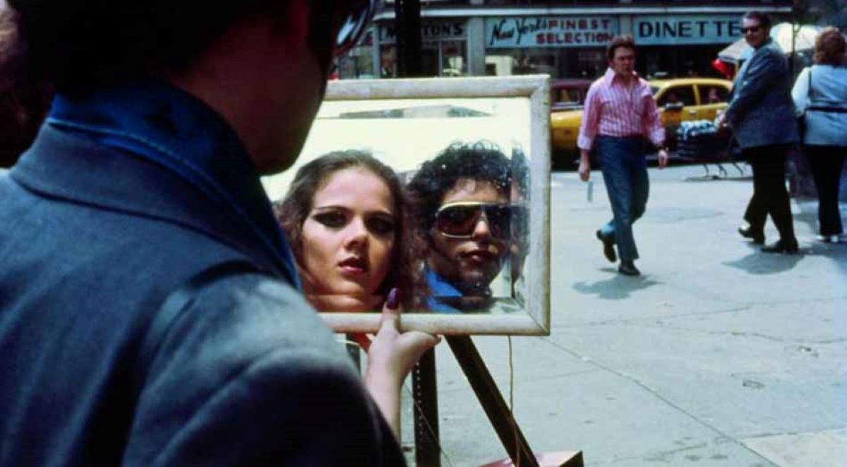 Photo of the mirror reflection of a man and a woman on a street