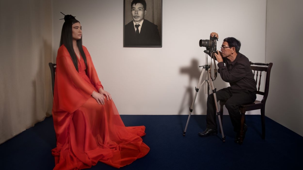 A woman with a red dress posing and a photographer taking her picture