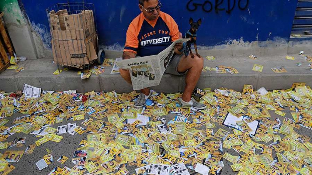 A Brazilian reads on a sidewalk littered with campaign propoganda. (AP)