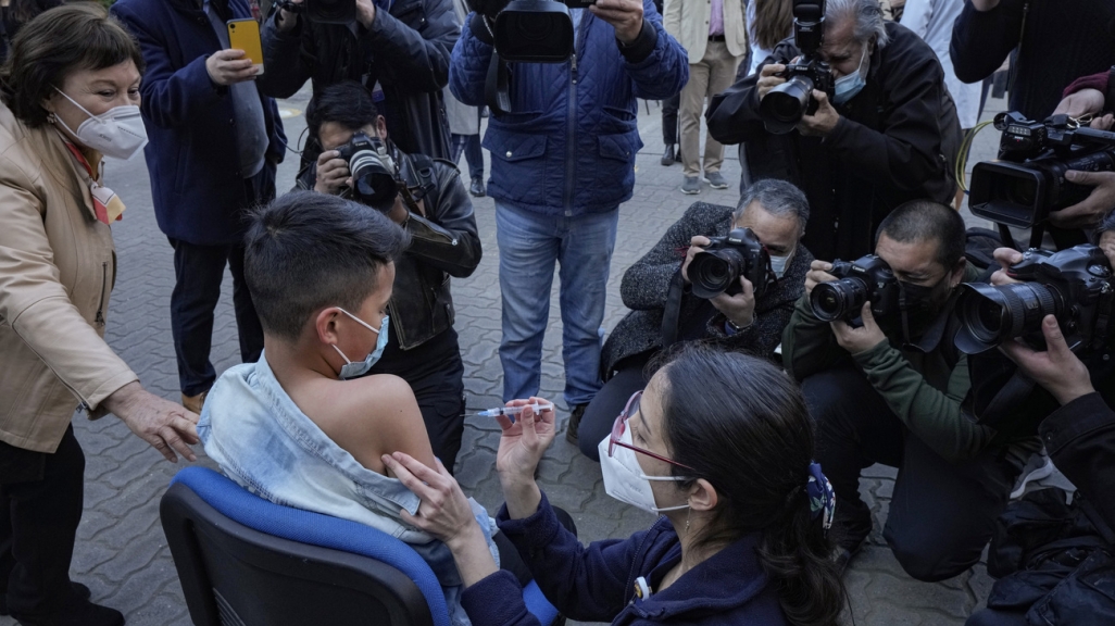 Photographers take pictures of a child receiving a Covid-19 vaccine in Chile. (AP)