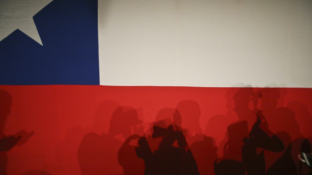Silhouettes against the Chilean flag. (AP)