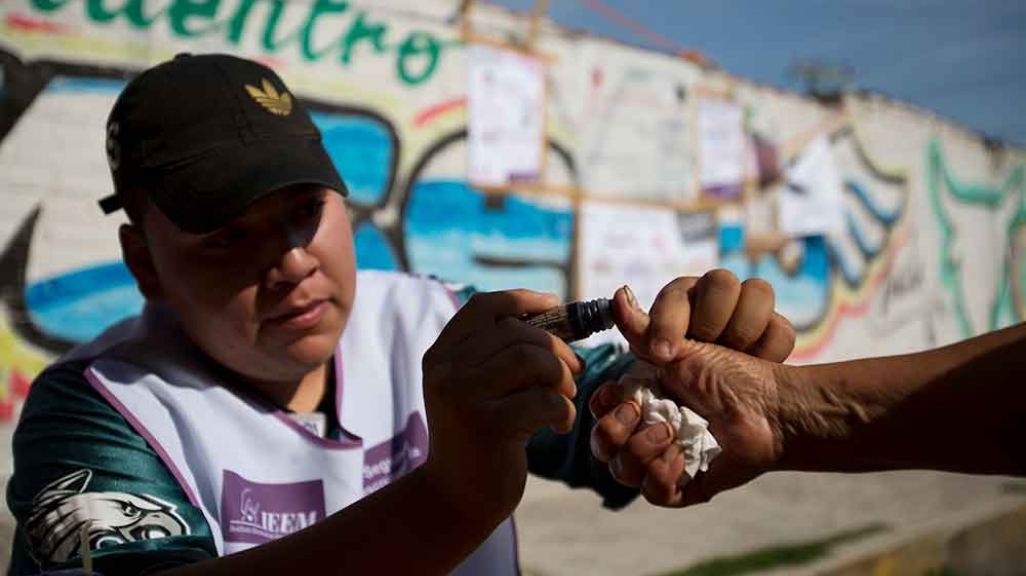 An Mexican election worker marks a voter's thumb with ink.