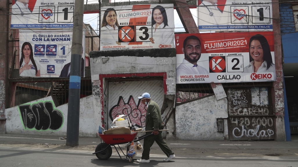 A man walks by campaign posters in Lima. (AP)