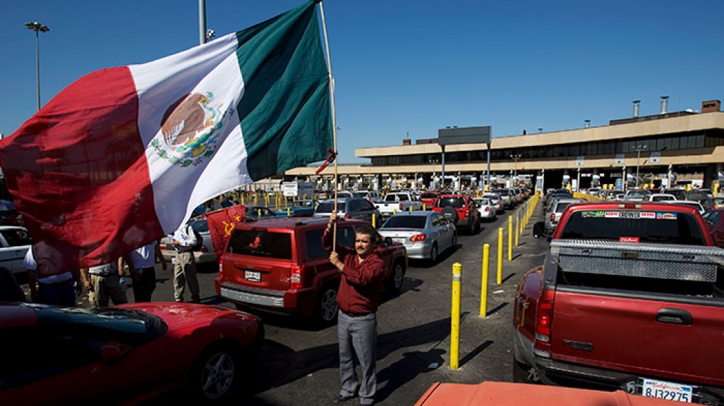 A man waves a flag at the Tijuana-San Diego border crossing.