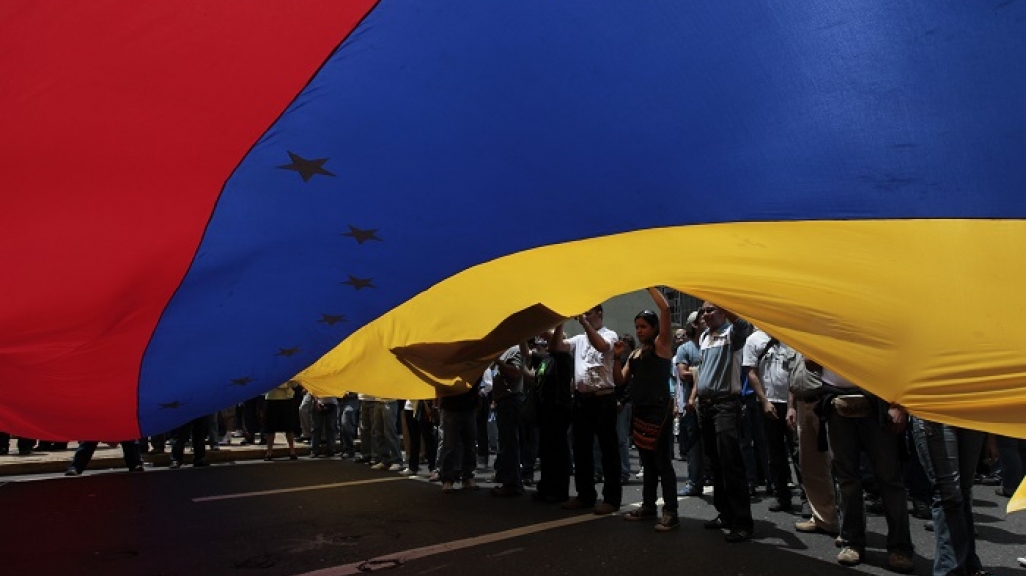 Demonstrators unfurl a Venezuelan flag