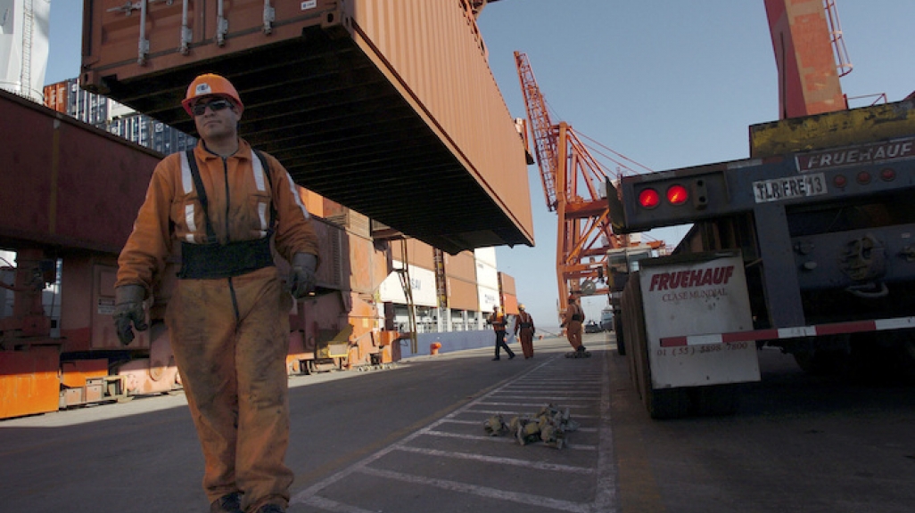 Workers unload a container vessel docked in Ensenada, Mexico.