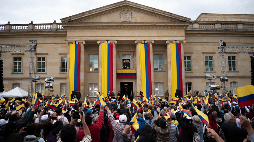 People gather at Colombia's presidential palace in Bogotá waving the yellow, blue, and red flag. (AP)