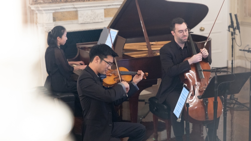 A violinist, cellist, and pianist perform.