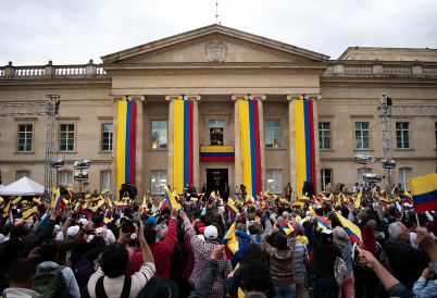 People gather at Colombia's presidential palace in Bogotá waving the yellow, blue, and red flag. (AP)