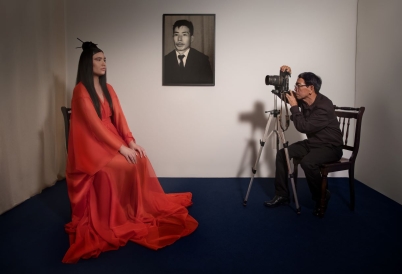 A woman with a red dress posing and a photographer taking her picture