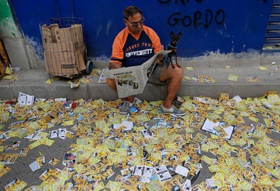 A Brazilian reads on a sidewalk littered with campaign propoganda. (AP)