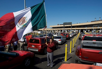 A man waves a flag at the Tijuana-San Diego border crossing.
