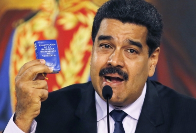 Nicolas Maduro holding a tiny constitution