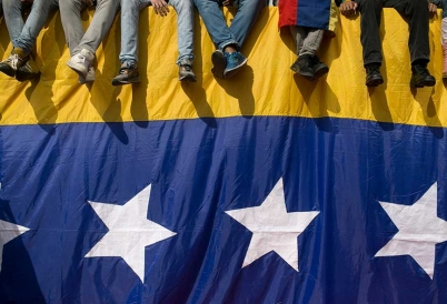 Venezuelans sit on a flag-draped wall. 