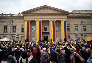 People gather at Colombia's presidential palace in Bogotá waving the yellow, blue, and red flag. (AP)
