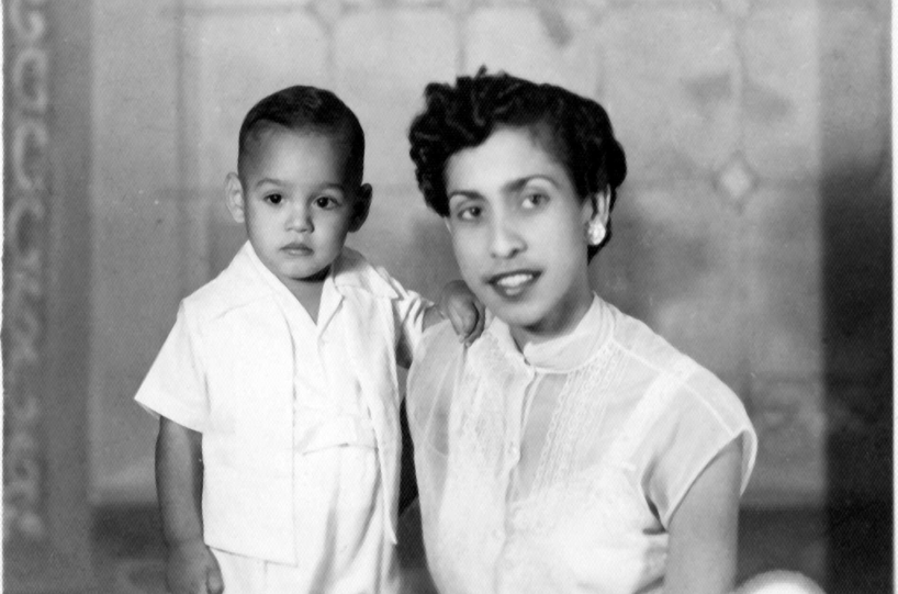 A black and white photo of a well-dressed young Latina woman with short hair posing with a young child, both in white clothing.
